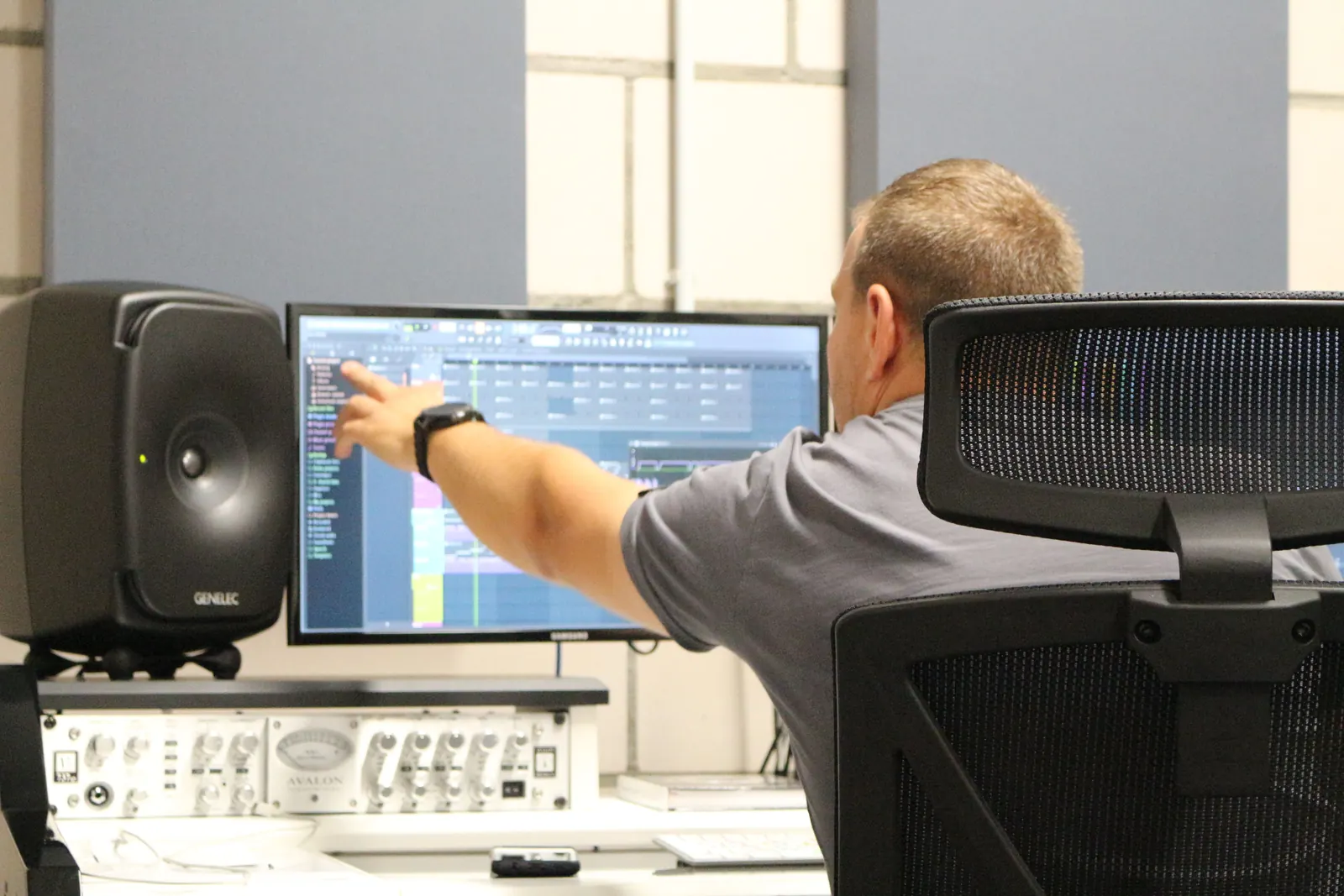 Ein Toningenieur zeigt am Monitor im MMO Studio auf die Aufnahmesoftware